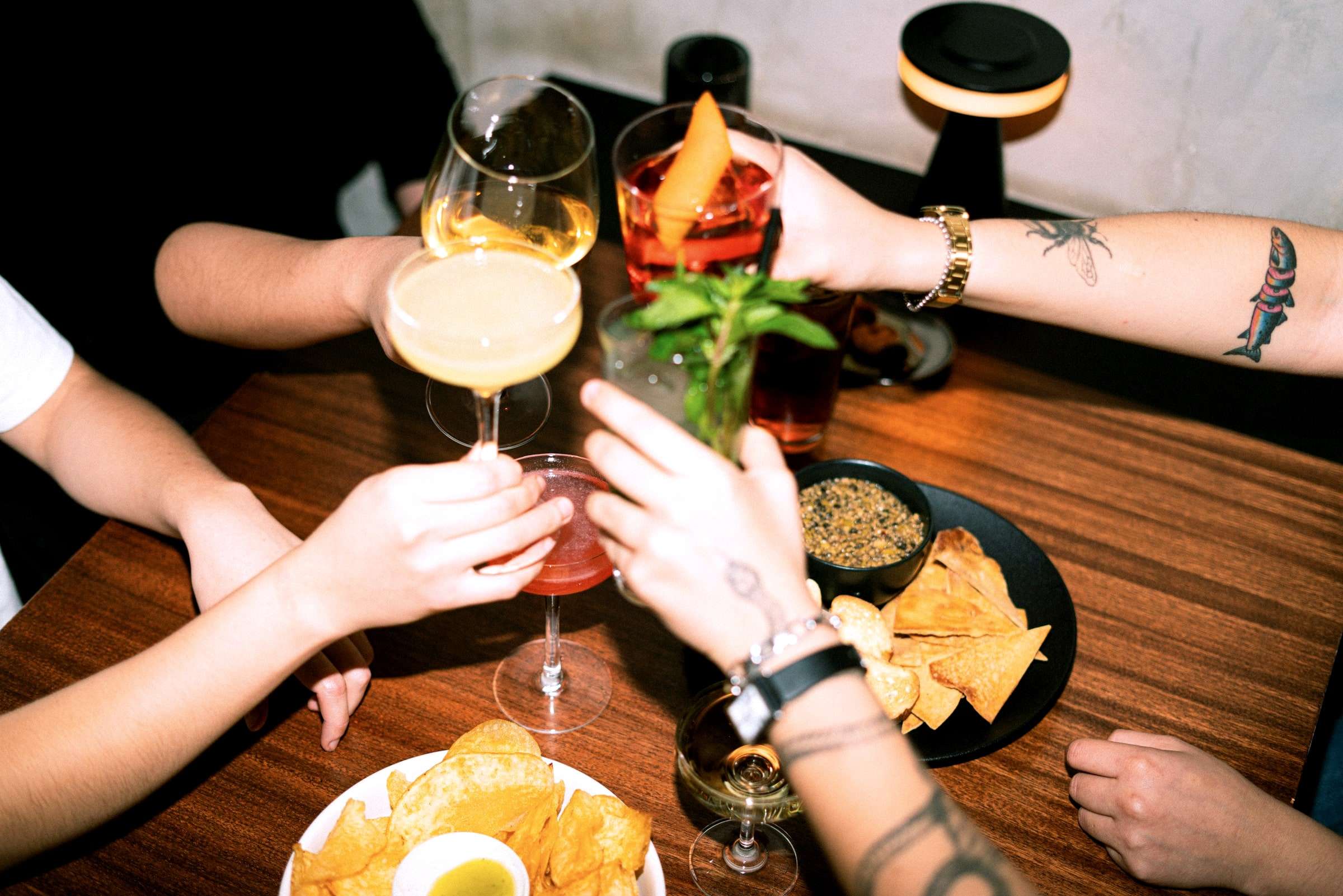 Hände mit Drinks und Snacks auf einem Tisch