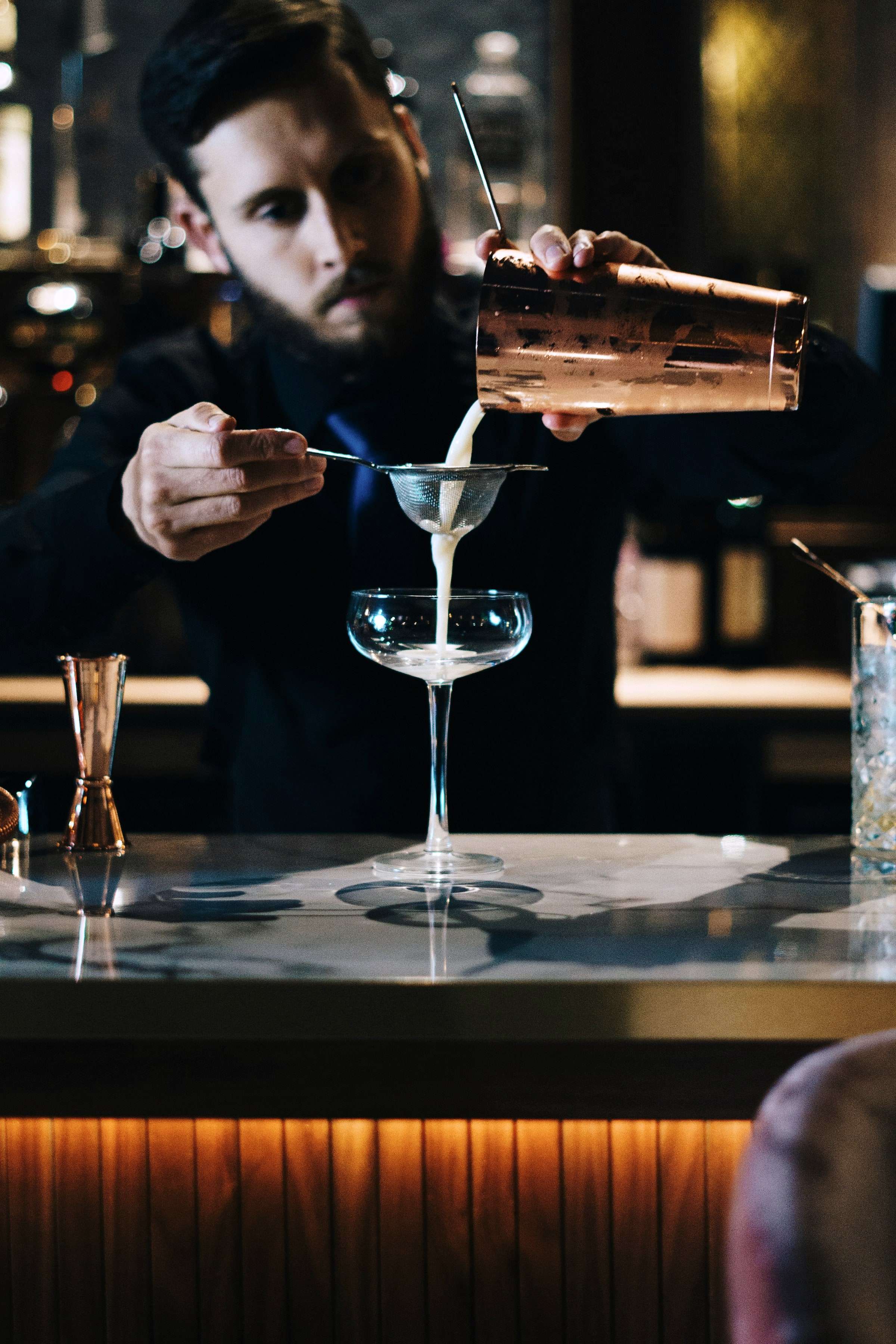 Barkeeper mixt einen Cocktail vor dunklem Hintergrund