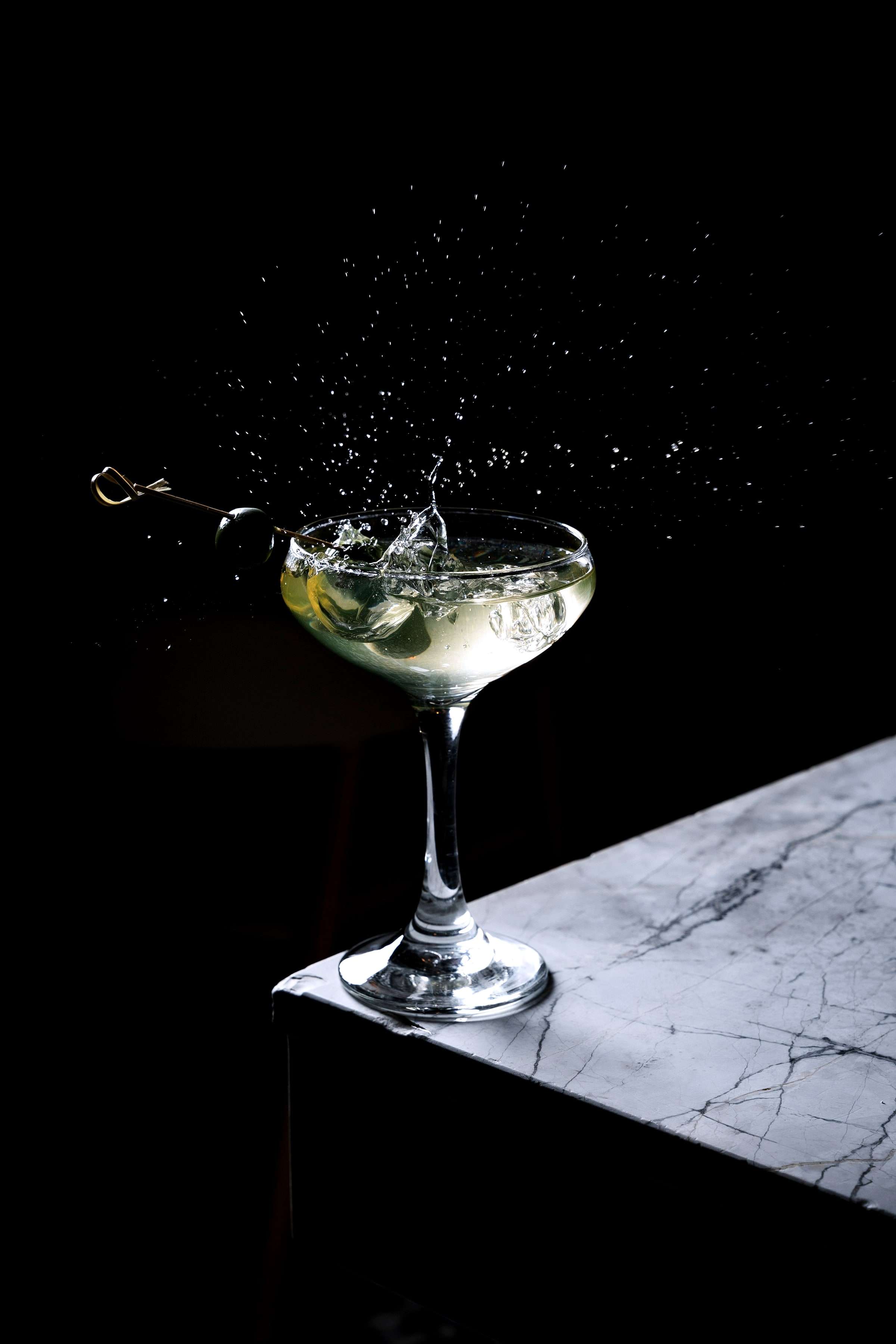 Cocktailglas mit Spritzer vor dunklem Hintergrund